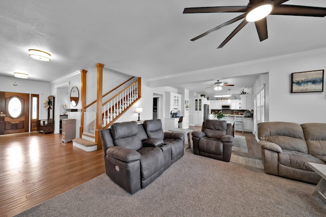 living area featuring ceiling fan, stairway, wood finished floors, and crown molding