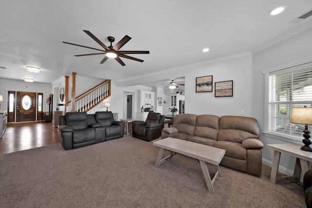 carpeted living room with visible vents, plenty of natural light, stairs, and ornamental molding