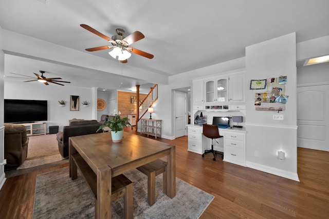 dining area featuring built in desk, stairway, ceiling fan, and wood finished floors