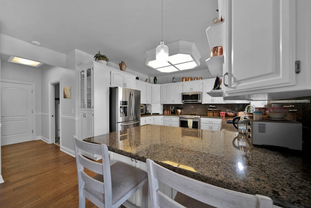 kitchen with backsplash, dark wood-style floors, white cabinetry, appliances with stainless steel finishes, and a peninsula