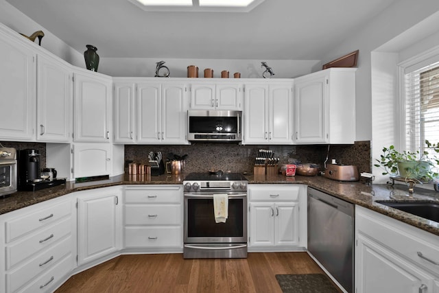 kitchen with dark wood-style floors, white cabinets, stainless steel appliances, and backsplash