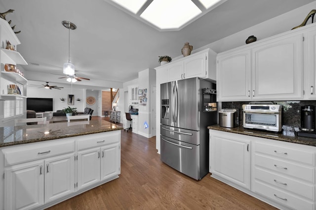 kitchen featuring dark stone countertops, light wood finished floors, stainless steel fridge with ice dispenser, white cabinetry, and tasteful backsplash