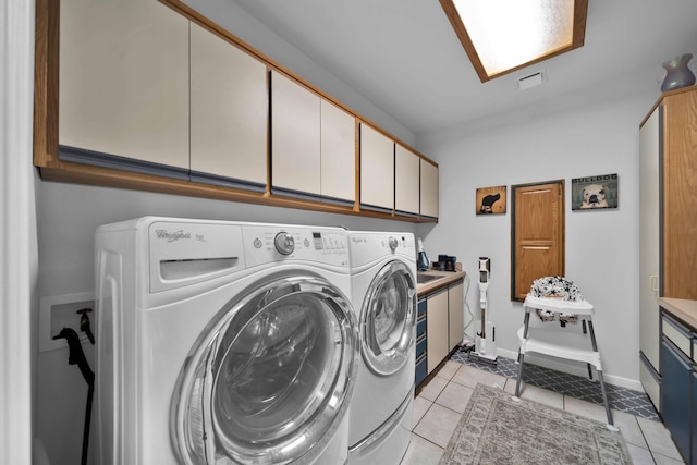 clothes washing area with visible vents, cabinet space, separate washer and dryer, light tile patterned flooring, and baseboards