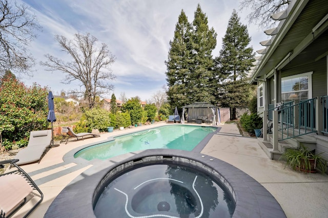 pool with a patio area, an in ground hot tub, and a gazebo