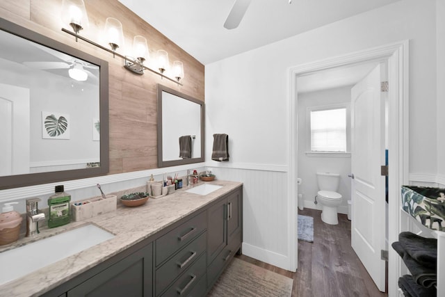 bathroom featuring a sink, toilet, wood finished floors, and a ceiling fan