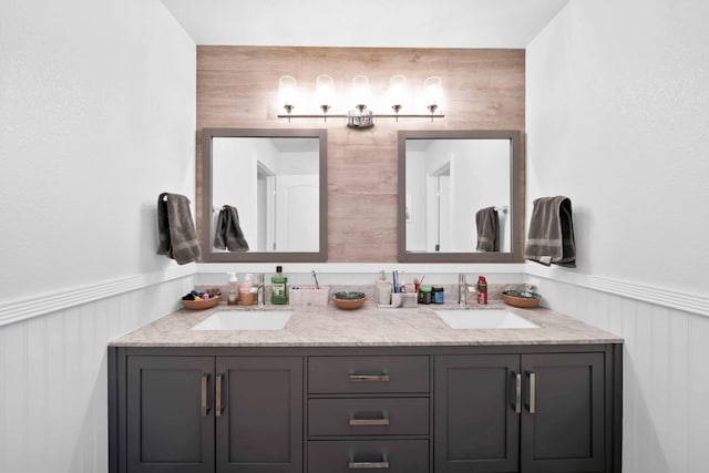 bathroom with a sink, double vanity, and wainscoting