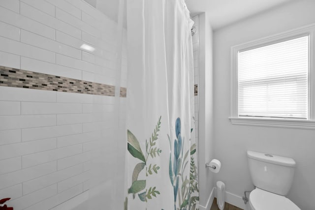 bathroom featuring a shower with curtain, baseboards, and toilet