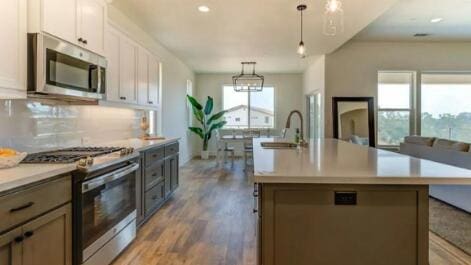 kitchen with tasteful backsplash, pendant lighting, light countertops, appliances with stainless steel finishes, and a sink