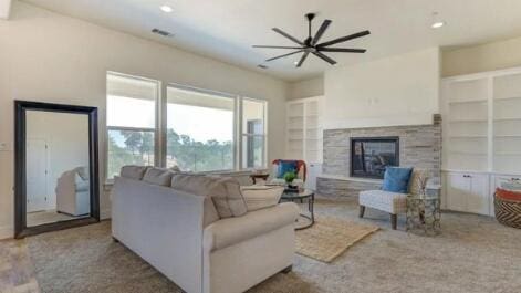 living area with a stone fireplace, built in features, recessed lighting, and ceiling fan