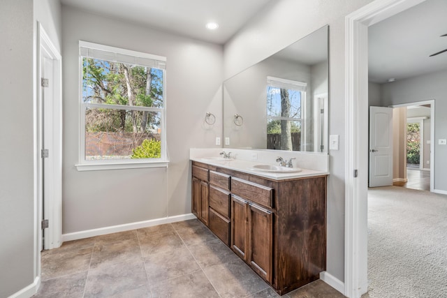 full bathroom with a healthy amount of sunlight, baseboards, and a sink