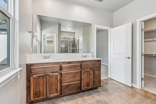 bathroom with a spacious closet, plenty of natural light, a shower stall, and a sink