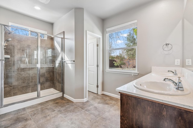 full bathroom with double vanity, a shower stall, and a sink