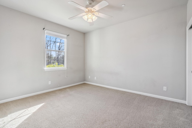 carpeted empty room featuring ceiling fan and baseboards