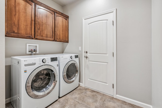 washroom featuring baseboards, cabinet space, and washer and clothes dryer