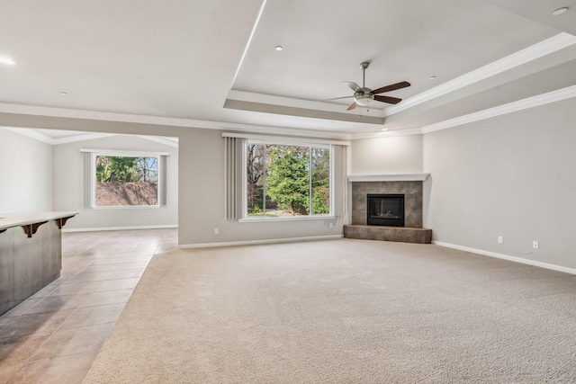 unfurnished living room with a wealth of natural light, a fireplace, and a tray ceiling