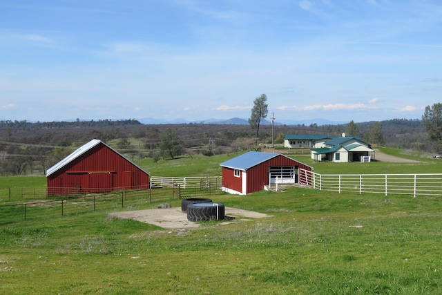 view of yard featuring a rural view, an outdoor structure, an outbuilding, and an exterior structure