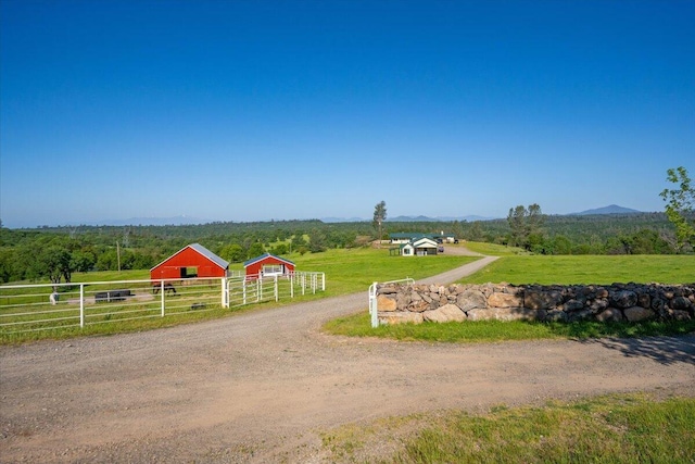 view of community with fence, a pole building, a rural view, an outdoor structure, and a mountain view