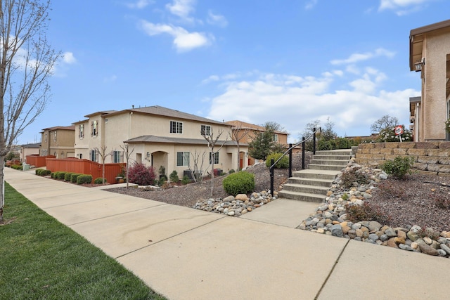 view of side of property featuring stucco siding, stairs, and fence