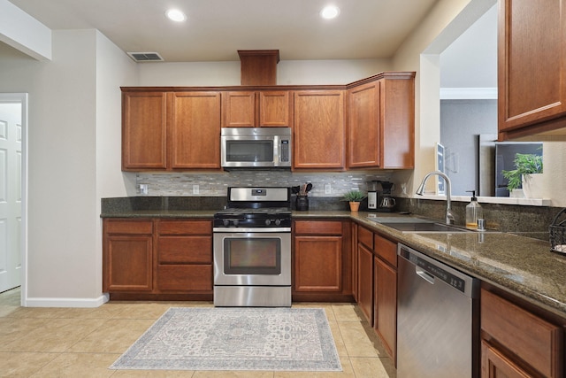 kitchen featuring visible vents, a sink, stainless steel appliances, light tile patterned floors, and decorative backsplash