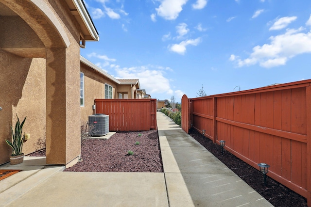 exterior space featuring a patio area, central AC unit, fence, and stucco siding