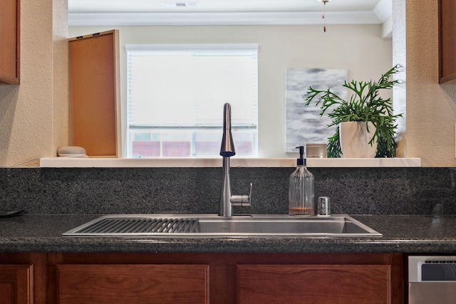 kitchen with dark countertops, plenty of natural light, brown cabinetry, and a sink