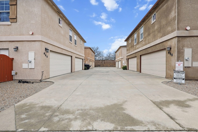 view of side of property featuring a garage, concrete driveway, and stucco siding