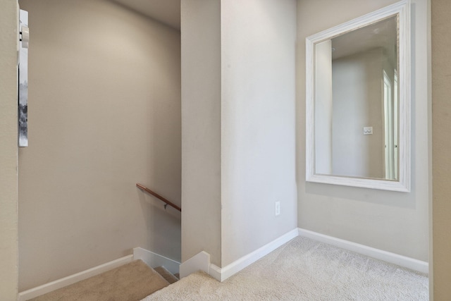 hall featuring an upstairs landing, carpet flooring, and baseboards