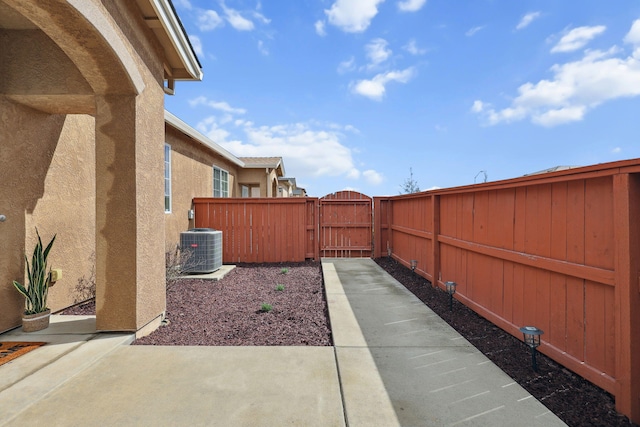 view of yard with a patio area, central air condition unit, fence, and a gate