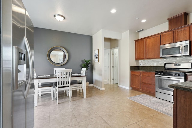 kitchen featuring backsplash, baseboards, light tile patterned floors, appliances with stainless steel finishes, and brown cabinetry