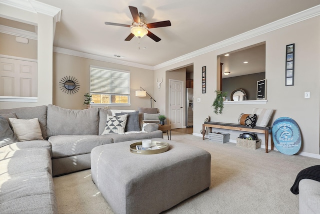 carpeted living room with baseboards, a ceiling fan, and crown molding