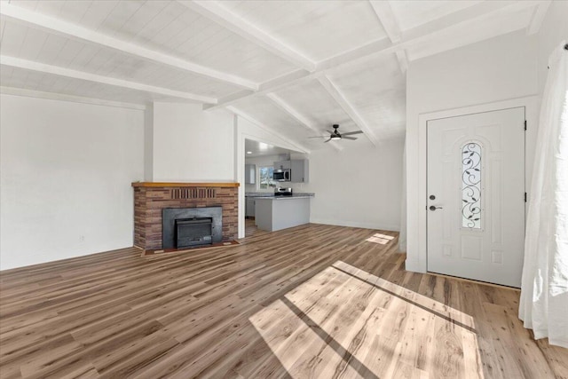 entrance foyer with lofted ceiling with beams, light wood-type flooring, a ceiling fan, and a brick fireplace