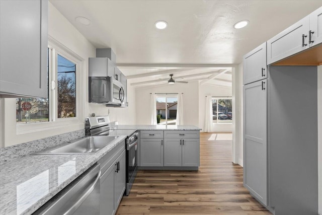 kitchen featuring lofted ceiling with beams, stainless steel appliances, light wood-style floors, a peninsula, and ceiling fan