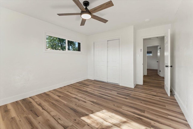 unfurnished bedroom with a closet, a ceiling fan, baseboards, and wood finished floors