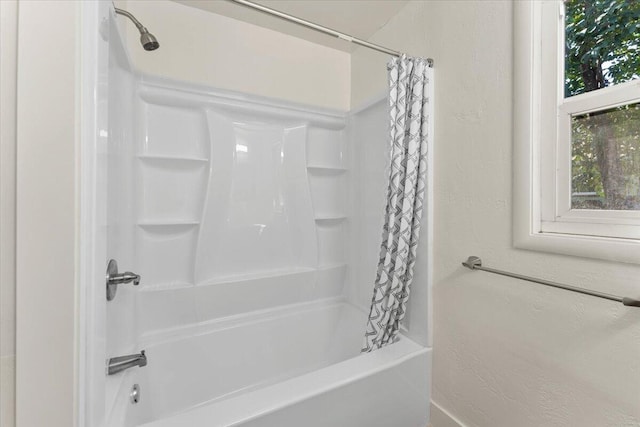 bathroom with shower / bath combo with shower curtain and a textured wall