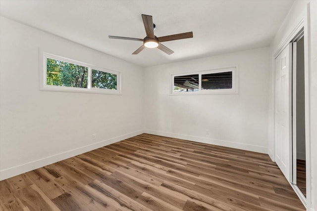 unfurnished bedroom with a closet, a ceiling fan, baseboards, and wood finished floors