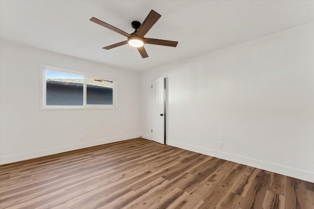 empty room with light wood-style flooring, a ceiling fan, and baseboards