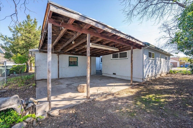 back of house with a patio area, a carport, fence, and crawl space