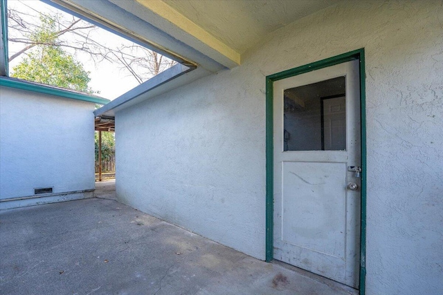 entrance to property featuring a patio and stucco siding