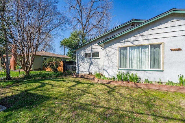 view of home's exterior featuring a lawn and fence