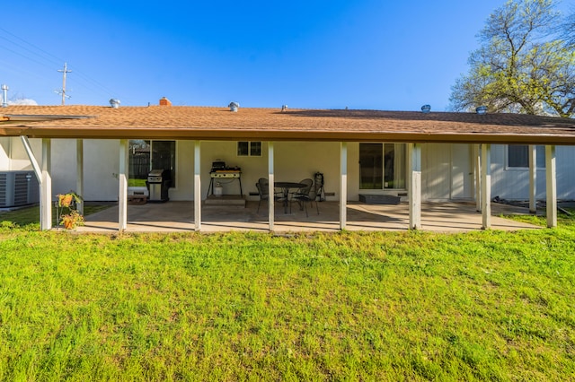 rear view of house with stucco siding, a patio, a lawn, and central air condition unit