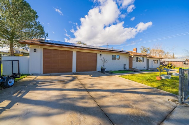 ranch-style home featuring solar panels, a garage, and fence