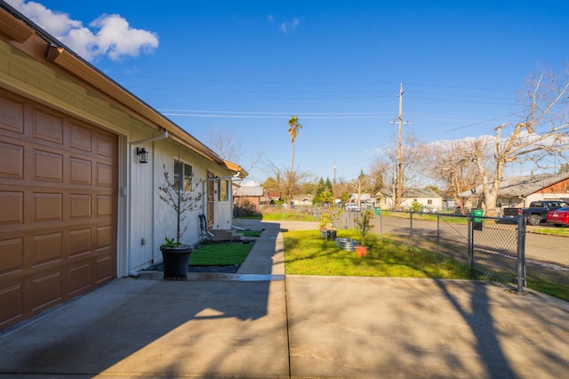 view of yard featuring a garage, a residential view, driveway, and fence