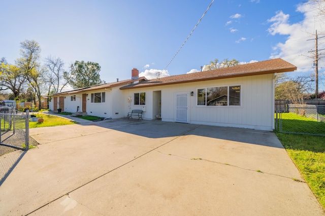view of front of house with a front lawn, fence, a chimney, a patio area, and driveway