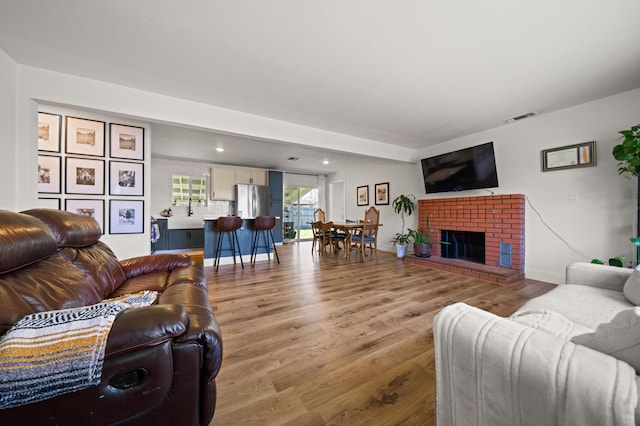 living area featuring visible vents, baseboards, a fireplace, recessed lighting, and light wood-type flooring