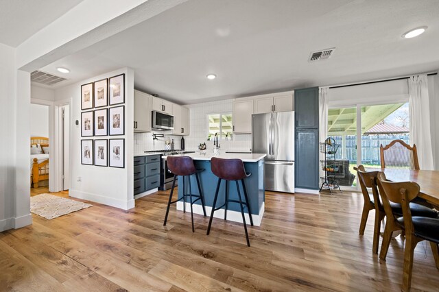 kitchen with stainless steel appliances, light wood finished floors, visible vents, and light countertops
