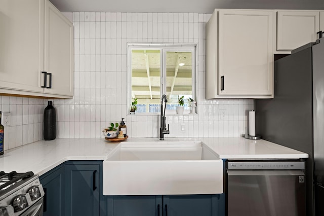 kitchen with a sink, decorative backsplash, blue cabinets, and stainless steel appliances