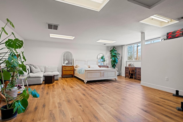 bedroom with visible vents, light wood-type flooring, and baseboards