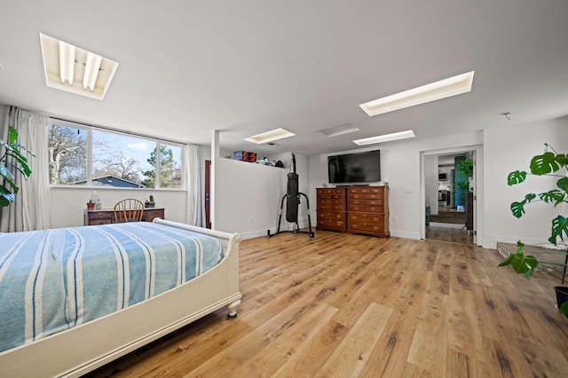 bedroom with attic access, light wood-style floors, and baseboards
