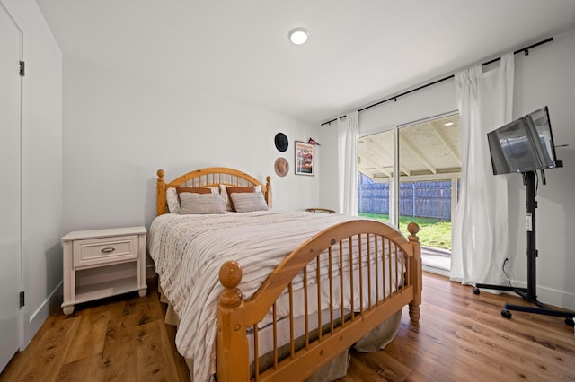 bedroom with access to exterior, wood finished floors, and baseboards