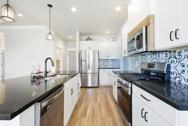 kitchen with backsplash, light wood-style flooring, white cabinets, stainless steel appliances, and a sink